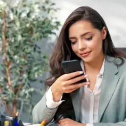 Frau bedient Smartphone in Ihrer Werbeagentur Essen
