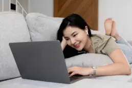 Frau sitzt vor dem Laptop und scrollt durch Social Media