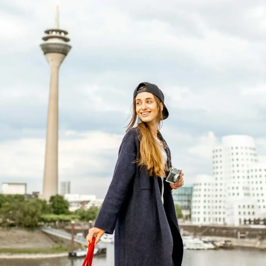 Junge Frau steht in Düsseldorf vor dem Rheinturm